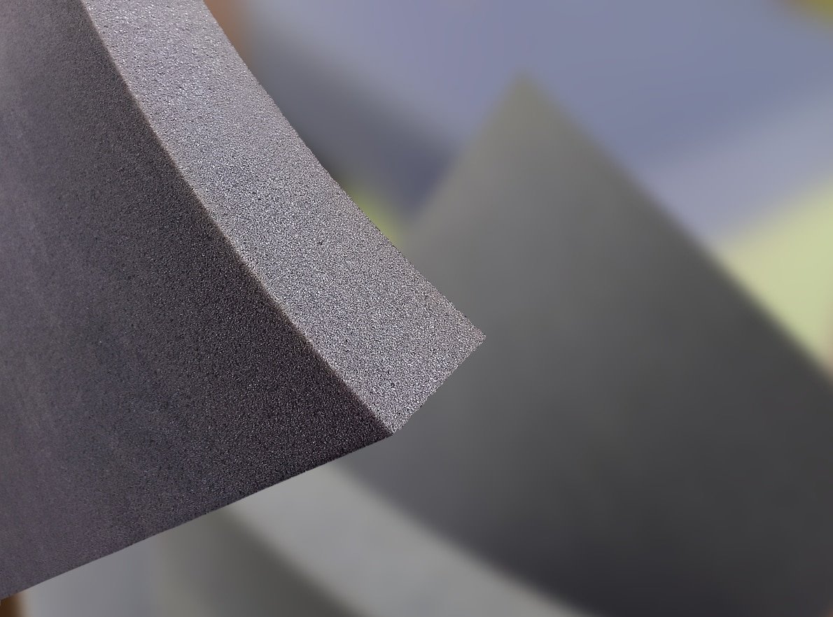 Close-up of charcoal grey UV resistant foam, highlighting its dense, porous texture and sharp rectangular edge.